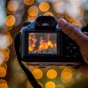 hand holding digital camera bokeh lights background 1