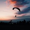 horizontal shot beach with person gliding down paramotor parachute