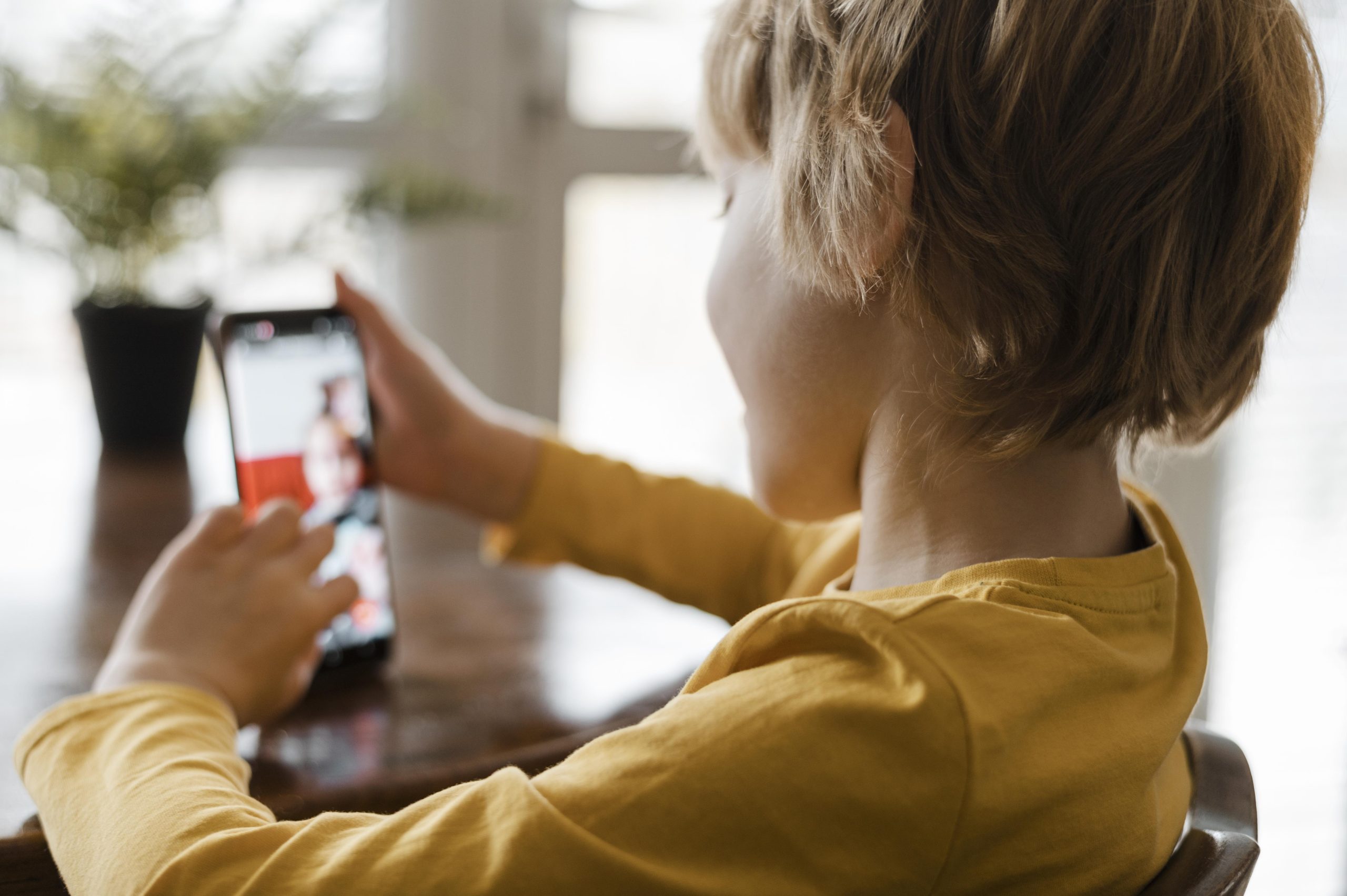 side view boy using smartphone home scaled