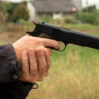 cropped hands thief holding gun field