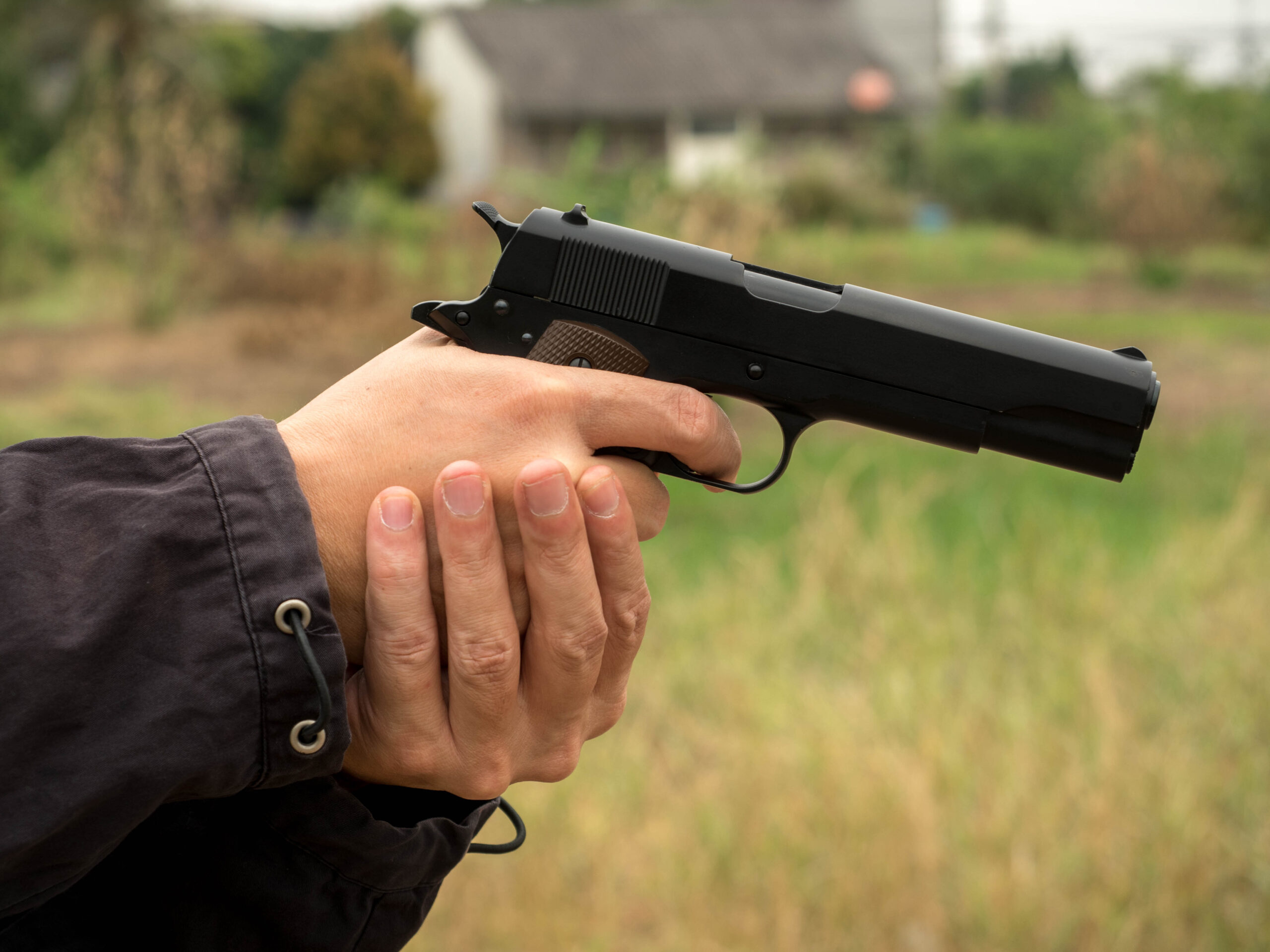cropped hands thief holding gun field scaled
