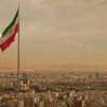 iran flag in the wind above skyline of tehran