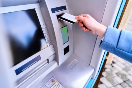 person insert plastic credit card into street atm bank withdrawing money