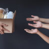 hand giving box various foods many hands dark gray background donation charity concept